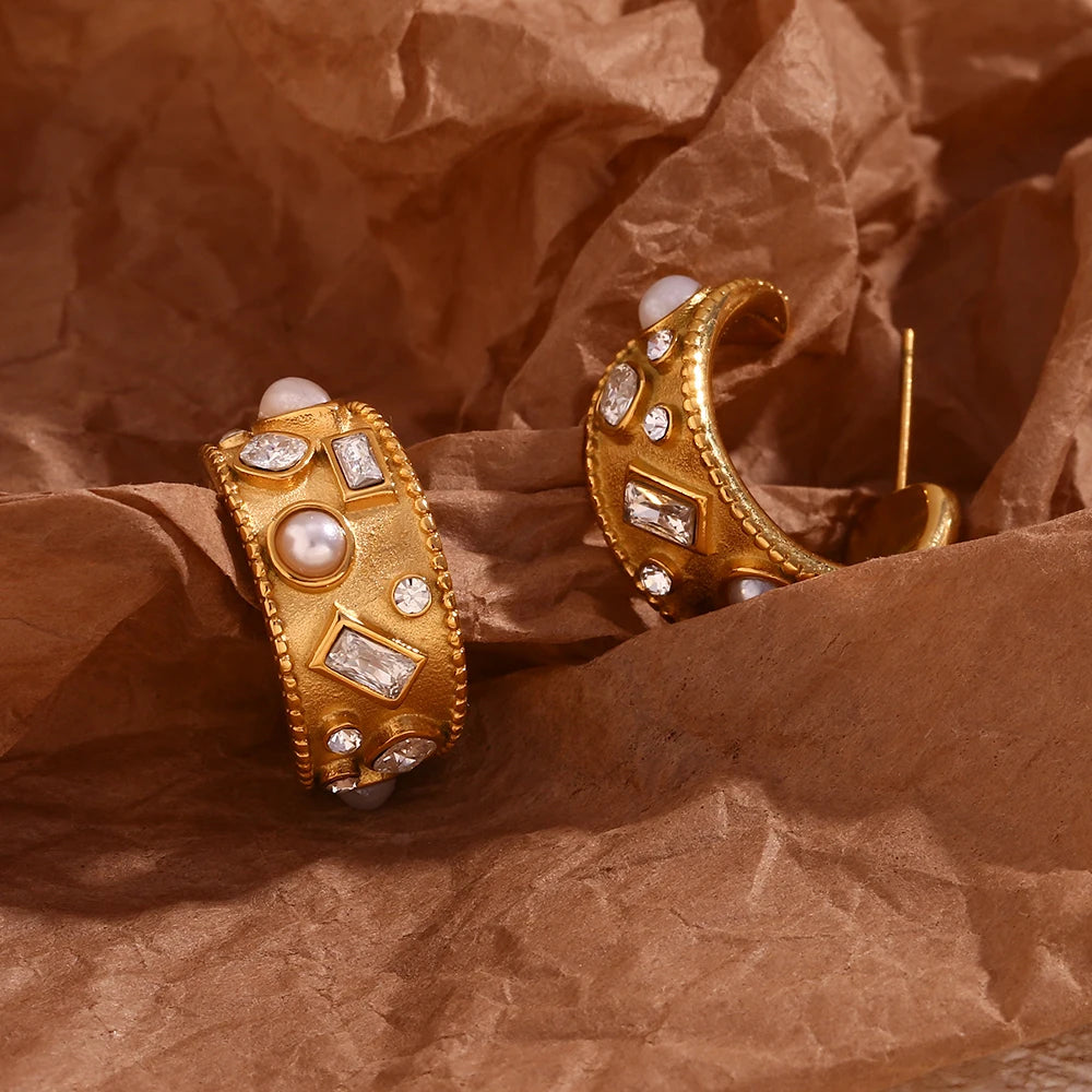 Gold earrings with pearls and gemstones on brown crumpled paper