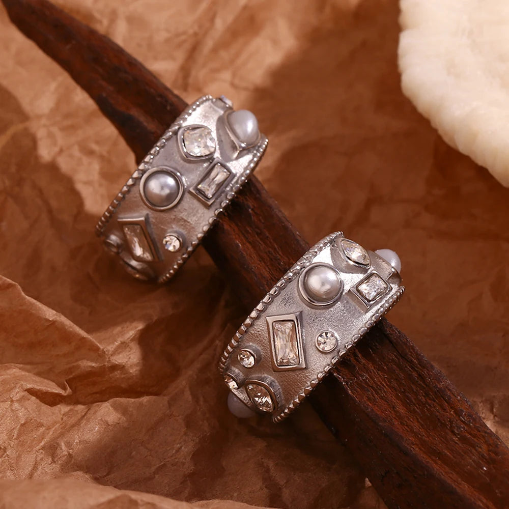Decorative silver earrings with intricate designs on a textured brown background
