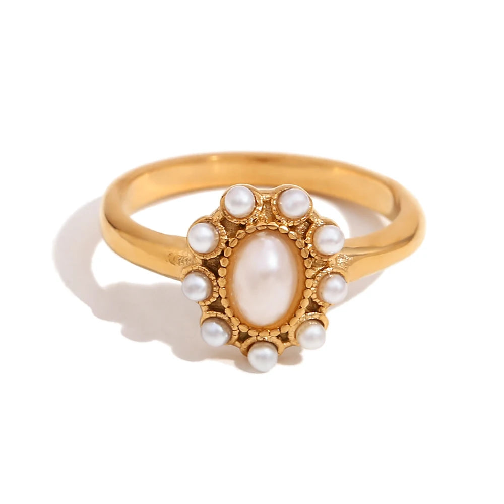 Gold ring with a central pearl and smaller pearls on a white background