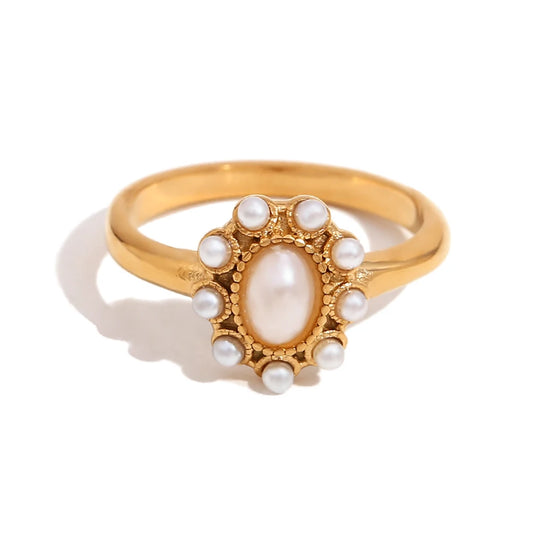Gold ring with a central pearl and smaller pearls on a white background