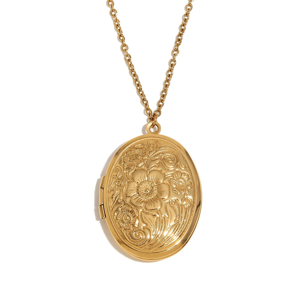 An oval-shaped gold locket necklace with vintage-inspired engravings, attached to a gold chain.