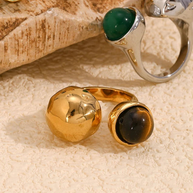 An 18K gold platted ring with a round tiger's eye stone on a hammer textured, asymmetrical band.