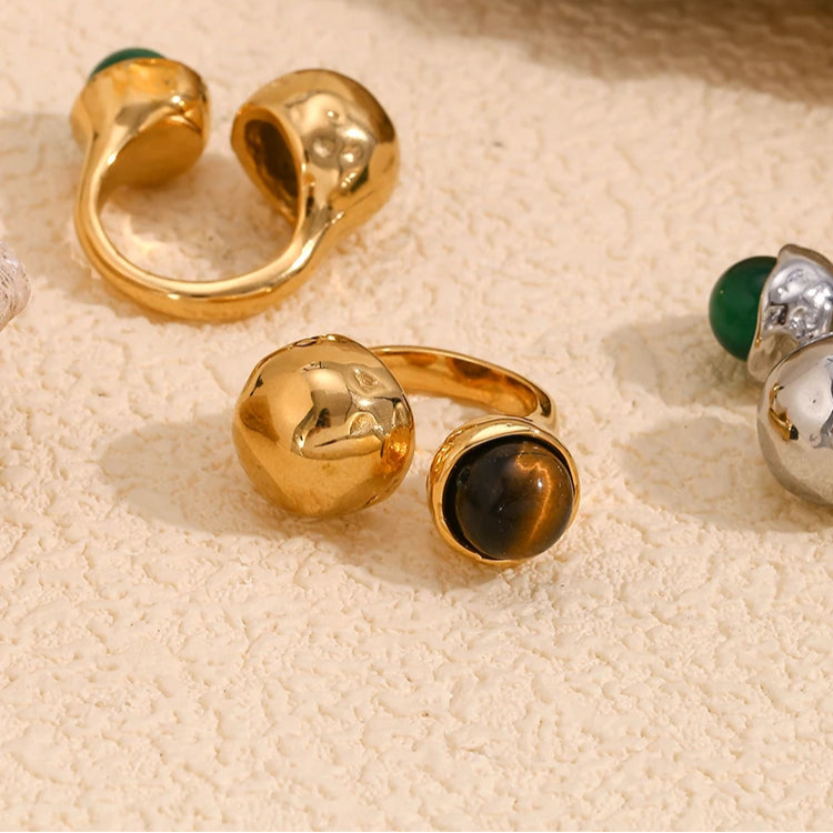 An 18K gold platted ring with a round tiger's eye stone on a hammer textured, asymmetrical band.