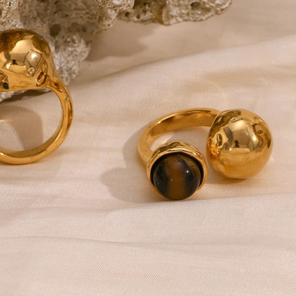 An 18K gold platted ring with a round tiger's eye stone on a hammer textured, asymmetrical band.