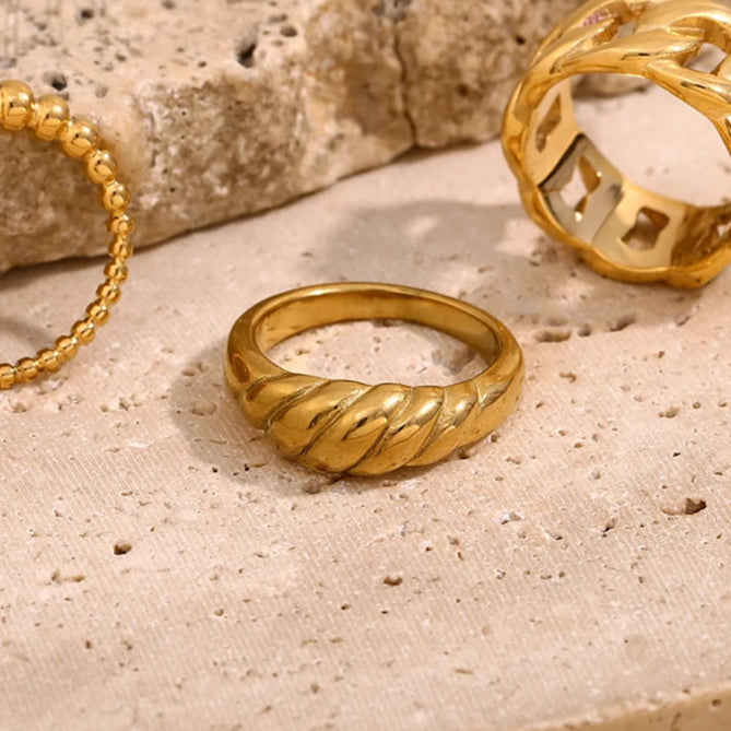 A modern gold stainless steel ring with a wrapped croissant shaped band.